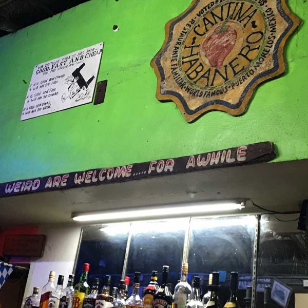 a sign above the bar reads, where the weird are welcome ... for awhile