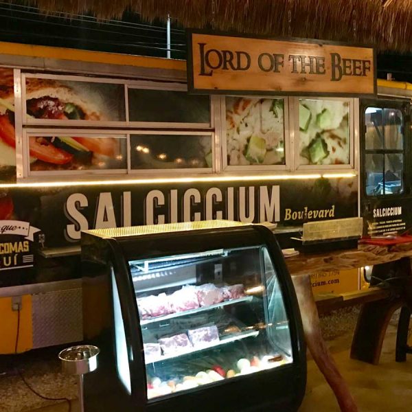 A yellow and black food truck parked near a street-side restaurant.