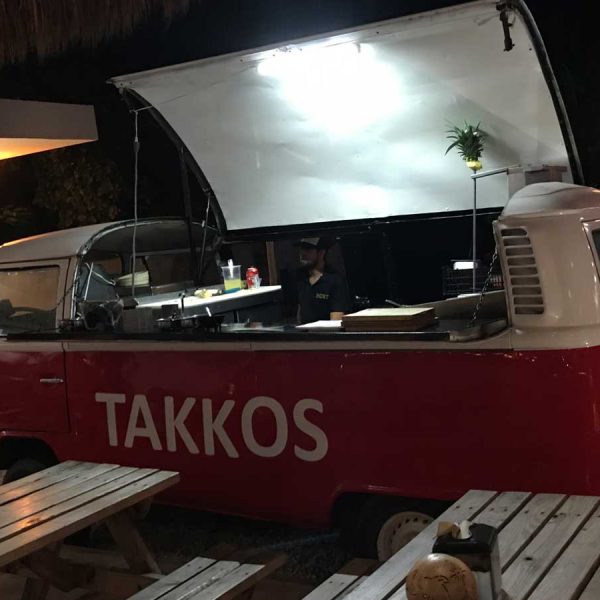 a bright red food van parked in front of wooden benches