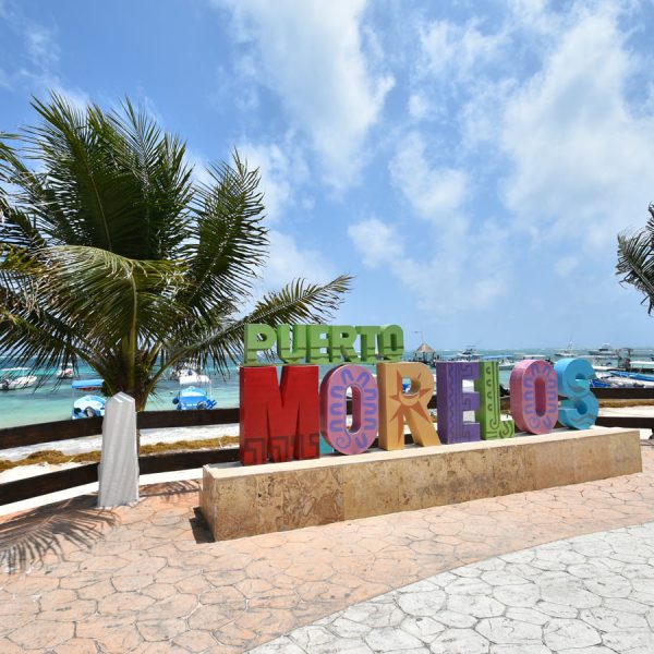 a sign with brightly painted letters reads, puerto morelos